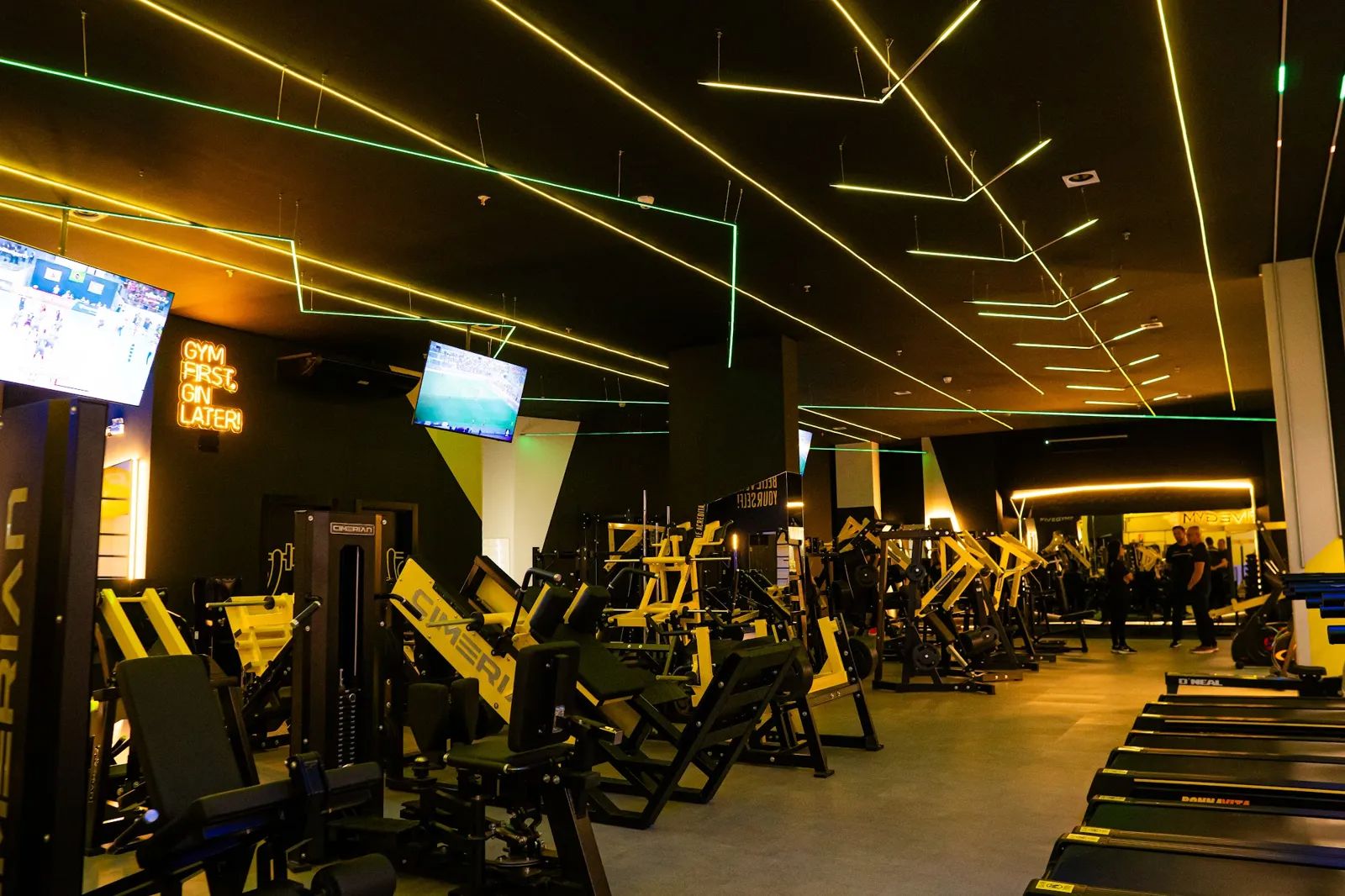 Salão de musculação da Five Gym com máquinas e linhas de luz no teto