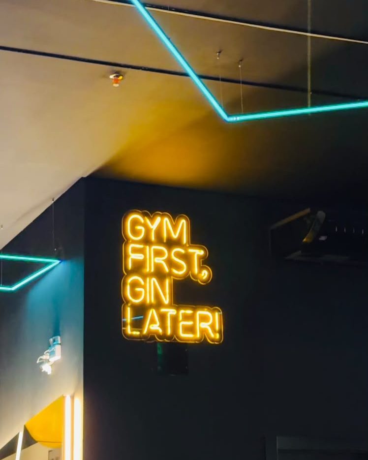 Letreiro neon Gym first, gin later na parede da Five Gym